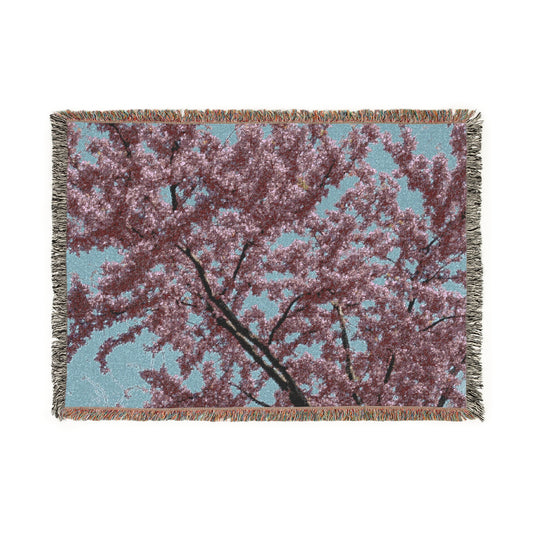 Woven blanket with cherry blossom design on a white background